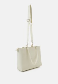 Sac fourre-tout beige au design structuré, avec des poignées doubles, une bandoulière réglable, des finitions en or et une texture lisse.