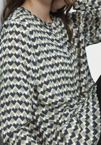 Camicia button-up con un motivo a diamante caratterizzata da tonalità di verde, blu navy e bianco. Realizzata in un tessuto testurizzato con maniche lunghe.