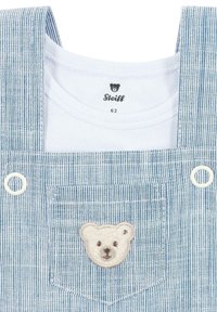 Blauwe en witte gestreepte tuinbroek met een beren gezichtspatch op de zak en een witte katoenen shirt eronder, met een ronde halslijn.