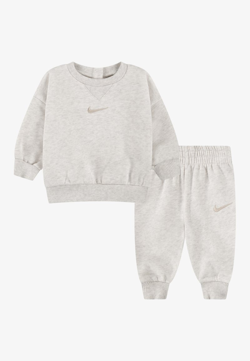 Sweatshirt en coton gris avec un col rond côtelé et des poignets élastiques, associé à un pantalon de jogging assorti avec une taille élastique et un logo sur le côté.