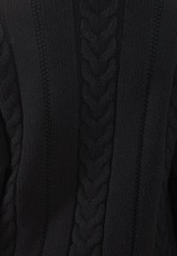 Mustmustri mustreega, kus on paks punutud muster keskel, tekstureeritud soonik külgedel ja pehme, jäme kangas.