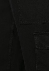 Svart tyg med en slät struktur har en sid söm och en lapplända, lämplig för skjortor eller ytterkläder.