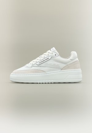 Hvid lav sneakers med tyk sål, beige ruskindsdetaljer, perforeret detalje på siden og "Copenhagen Studios" branding på snørebåndsområdet.