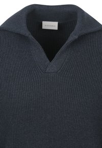 Donker marineblauwe v-halstrui van ribbelstructuur, met een opgevouwde kraag. Gemaakt van zacht materiaal met een discrete merklabel aan de binnenkant.