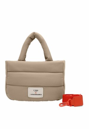 Beige gewatteerde handtas met afgeronde handvatten en een label, naast een afneembare felrode schouderriem met clip.