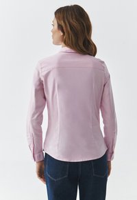 Camicia a maniche lunghe di colore rosa chiaro con dettagli in bottoni sui polsini e una texture liscia. Vestibilità sagomata con un design tailored.
