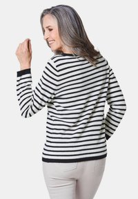 Gestreifter Pullover in Schwarz und Weiß mit langen Ärmeln und rundem Ausschnitt. Schwarzer gerippter Saum und Bündchen; weiche Stricktextur. Rückansicht.