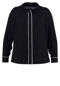 Blouse noire à manches longues avec bordure blanche le long de la patte de boutonnage et des poignets, comprenant un col classique et une fermeture avant par boutons.