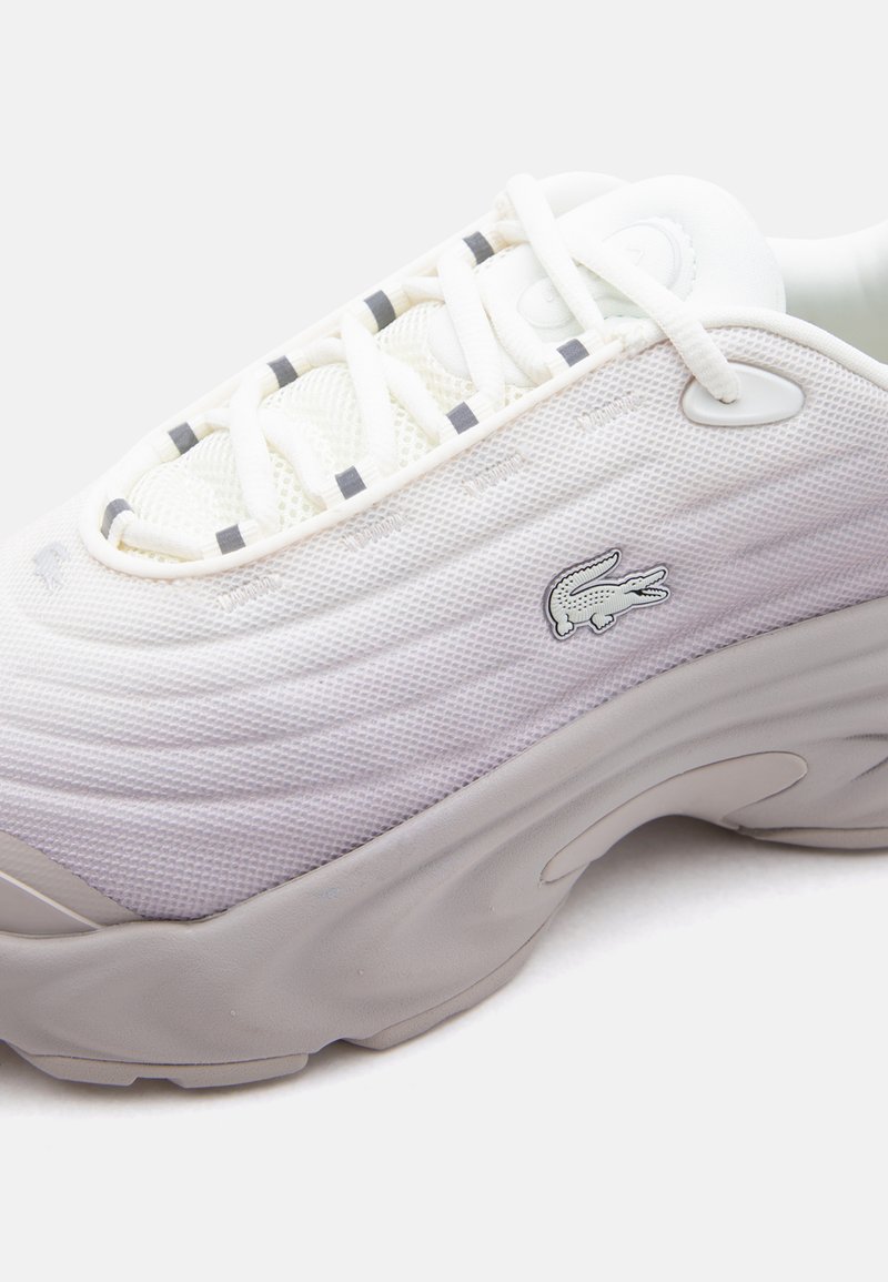 Weißer Sneaker mit niedrigem Schaft, Mesh-Obermaterial, grauer Sohle, weißen Schnürsenkeln und kleinem gesticktem Krokodil-Logo an der Seite.