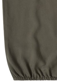 Tissu vert olive foncé avec ourlet élastique froncé et coutures visibles le long des bords.