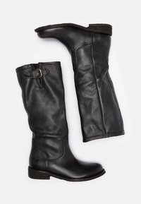 Bottes noires en cuir montantes avec un bout légèrement pointu, un petit talon empilé, un détail de boucle sur le côté et une texture lisse.