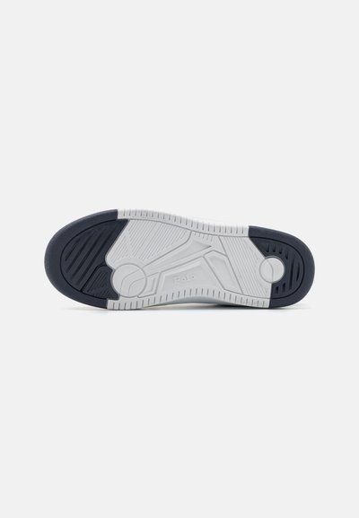 Suela de zapato en caucho azul marino y blanco, texturizada con una banda de rodadura con diseño para mayor tracción, que presenta un acento circular y un detalle de marca.