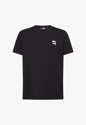 Juodas medvilninis marškinėliai su maža balta grafika, vaizduojančia veidą su vasariniais akiniais kairėje krūtinės pusėje. Trumpas rankoves ir apvalaus kaklo dizainas.