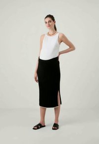 Musthave ribakandiga must seelik külje lõhe ja kontrastset äärestust. Kantud valge ilma varrukateta tipiga ja mustade libisemisseentega.
