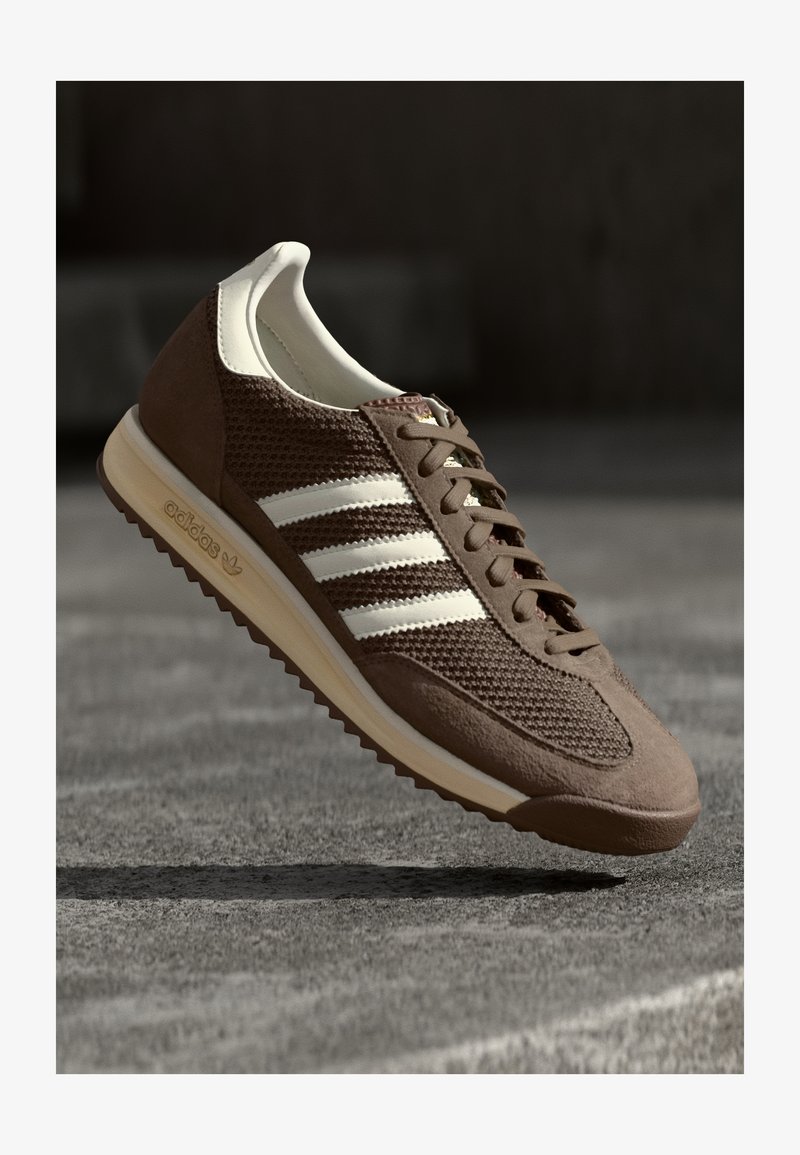 Pruun spordijalanõud, millel on võrgust pealis, sametised aktsendid ja kolm valget triipu. Omab ümarat varbaosa ja tekstuurset kummist tallat.