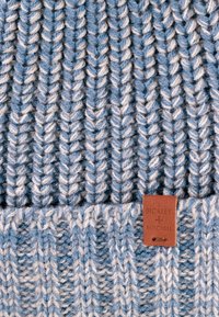 Czapka robiona na drutach w jasnoniebieskim i białym kolorze, z wyraźną fakturą prążkowaną. Zawiera brązową skórzaną metkę z logo "BICKLEY + MITCHELL".