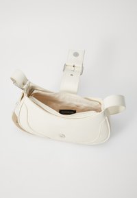 Sac à épaule en cuir blanc avec un design incurvé, quincaillerie argentée et un compartiment à fermeture éclair ouvert révélant un intérieur beige.