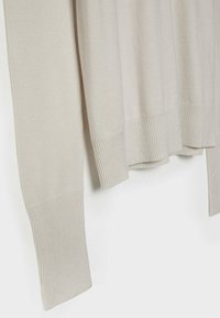 Vaalea beige neulepaita, jossa on ribbineuleiset hihansuut ja helma. Ominaisuuksiin kuuluu pitkät hihat ja rento malli. Materiaali vaikuttaa pehmeältä ja sileältä tekstuurilta.