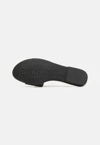 Suola di scarpa in gomma nera con motivi a righe orizzontali e verticali, caratterizzata dal testo impresso "CALVIN KLEIN JEANS" per il branding.