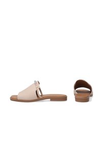 Beige slidesandaler med en glat overflade, åben tå og rygfri design. Har en dekorativ metalaccent foran og en flad sål.