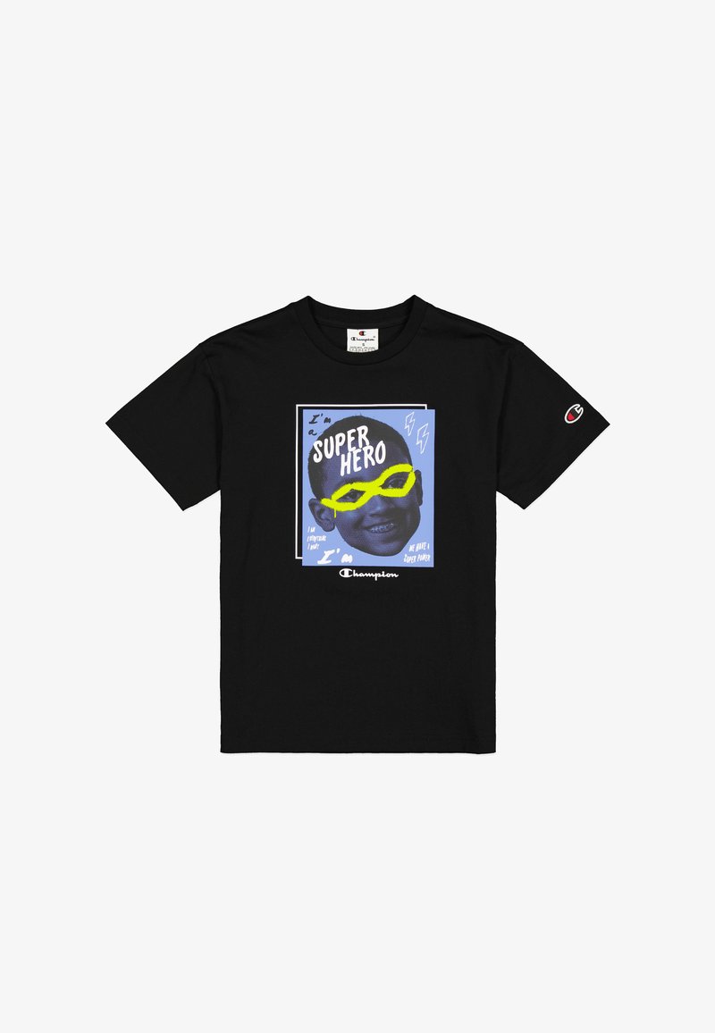 Camiseta de algodón negra con un estampado gráfico que muestra el rostro de un niño, gafas de sol amarillas y un texto en negrita que dice "Soy un SUPER HÉROE" sobre un fondo azul.