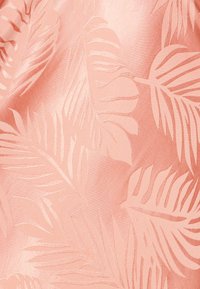 Tissu pêche avec un motif de feuilles en relief, présentant une texture lisse et un éclat brillant, mettant en valeur l'intrication du design du feuillage.