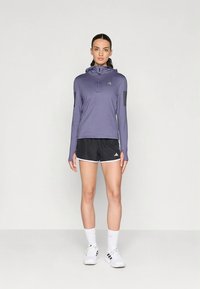 Light purple long-sleeve athletic top with a zip and hood, paired with black shorts. Both feature Adidas branding and contrasting trim.
