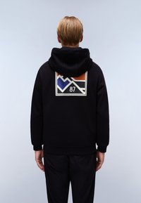 Sudadera negra con un diseño gráfico en la parte posterior que presenta elementos en naranja, azul y blanco, y el número "87" dentro de un cuadrado.