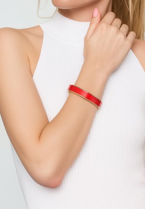 Red glossy cuff bracelet with gold-tone accents, featuring a sleek, wide design worn on a bare wrist. Background is plain white.