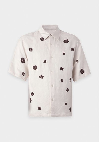 Chemise beige à manches courtes, boutonnée, avec petits motifs floraux marron dispersés et col classique sur fond uni.