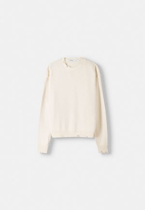 Maglione color crema con maniche lunghe, polsini e orlo a costine, tessuto leggero a maglia, caratterizzato da piccoli dettagli scuciti sulle spalle.