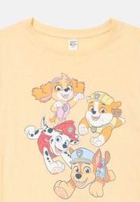 Gul t-shirt med fire animerede hunde: et pink, rødt og blåt uniformeret design med tegneseriepræg og legesyge ansigtsudtryk.