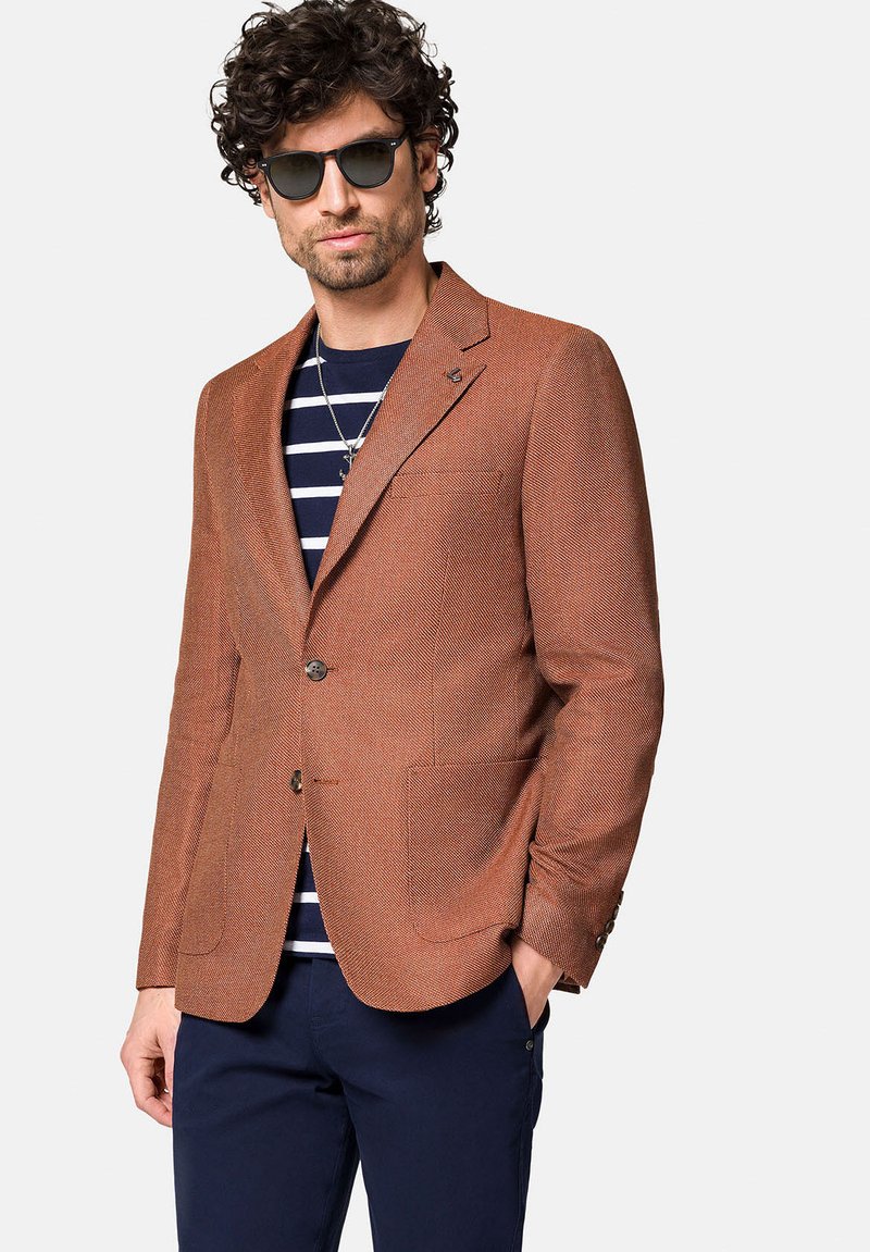 Brązowy żakiet o teksturowanej powierzchni z dopasowanym krojem, dwoma guzikami i bocznymi kieszeniami, nałożony na paskowany niebiesko-biały koszulę.