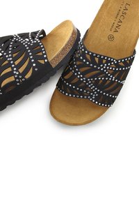 Zwarte slidesandalen met uitsneden in bladerenontwerp, versierd met zilveren rhinestones. Korken voetbed en een geblokt rubberen zool voor grip.