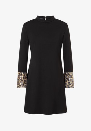 Robe noire à manches longues avec un col montant et des poignets ornés d'un motif léopard, décorée de sequins dorés et argentés.