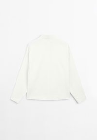 Chemise blanche à manches longues avec col mandarin, texture lisse et coupe droite. Présente une couture centrale dans le dos, design minimaliste.