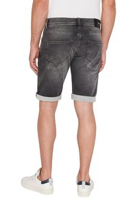 Shorts de mezclilla gris con puños enrollados, bolsillos traseros con una forma distintiva y un desvanecimiento sutil. Combinados con zapatillas blancas.