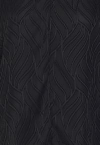 Tissu noir présentant un motif ondulé texturé, avec des éléments de couture en relief ajoutant de la profondeur et un intérêt visuel. Finition douce et lisse.