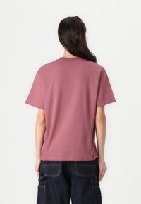 Kortärmad, avslappnad t-shirt i dammig rosafärgad bomullsmaterial. Har rund hals och en sömlös design utan dekorationer.
