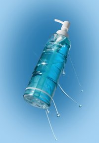 Bouteille en plastique transparent contenant une huile nettoyante bleue avec une pompe blanche, présentant un design élégant, avec des gouttelettes d'huile éclaboussant autour sur un fond bleu.