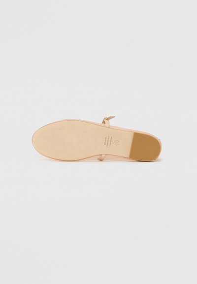Light tan heeled sandal with a smooth leather upper, slender ankle strap, and a flat rubber sole. Minimalist design with no visible patterns.