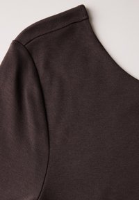 Sudadera marrón oscuro con un enfoque en su textura suave, costura de hombro redondeada y un diseño de escote simple.
