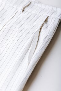 Ύφασμα με λευκές ρίγες και λεπτές μπλε γραμμές, με πιέτες και υφή. Το υλικό φαίνεται μαλακό και ελαφρύ.