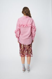 Pink striped shirt with ruffled accents, paired with a sheer burgundy skirt featuring floral embroidery. Clear heels and blue socks complete the look.