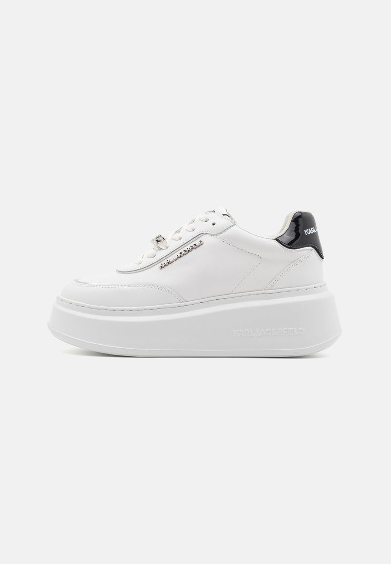 Baskets plateforme blanches avec une tige en cuir lisse, un empiècement en cuir verni noir au talon, un avant lacé et un détail de logo métallique sur le côté.