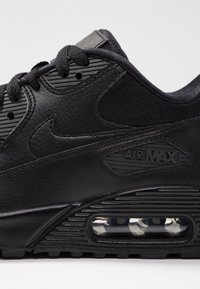 Czarny sneaker Nike Air Max z teksturowaną cholewką ze skóry i materiału, z widoczną jednostką amortyzującą powietrze oraz wytłoczonym logo.