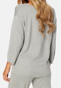 Maglione grigio chiaro in maglia con una vestibilità comoda e maniche a tre quarti, caratterizzato da un colletto rotondo e dettagli a coste ai polsini e all'orlo.