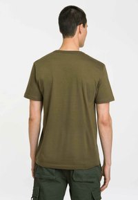 Olive green cotton t-shirt with short sleeves, crew neck, and straight hem. Smooth texture and minimal stitching details.