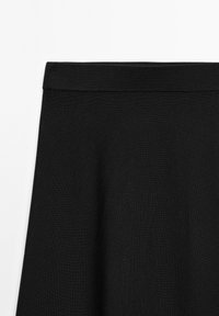 Black knitted skirt with a flat waistband. The fabric has a smooth texture and drapes softly, creating a flowing silhouette.