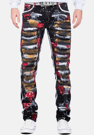 Jeans noirs usés avec de multiples éclaboussures de peinture en rouge, blanc et or. Coutures décoratives apparentes et une coupe fuselée, avec une taille décorative.